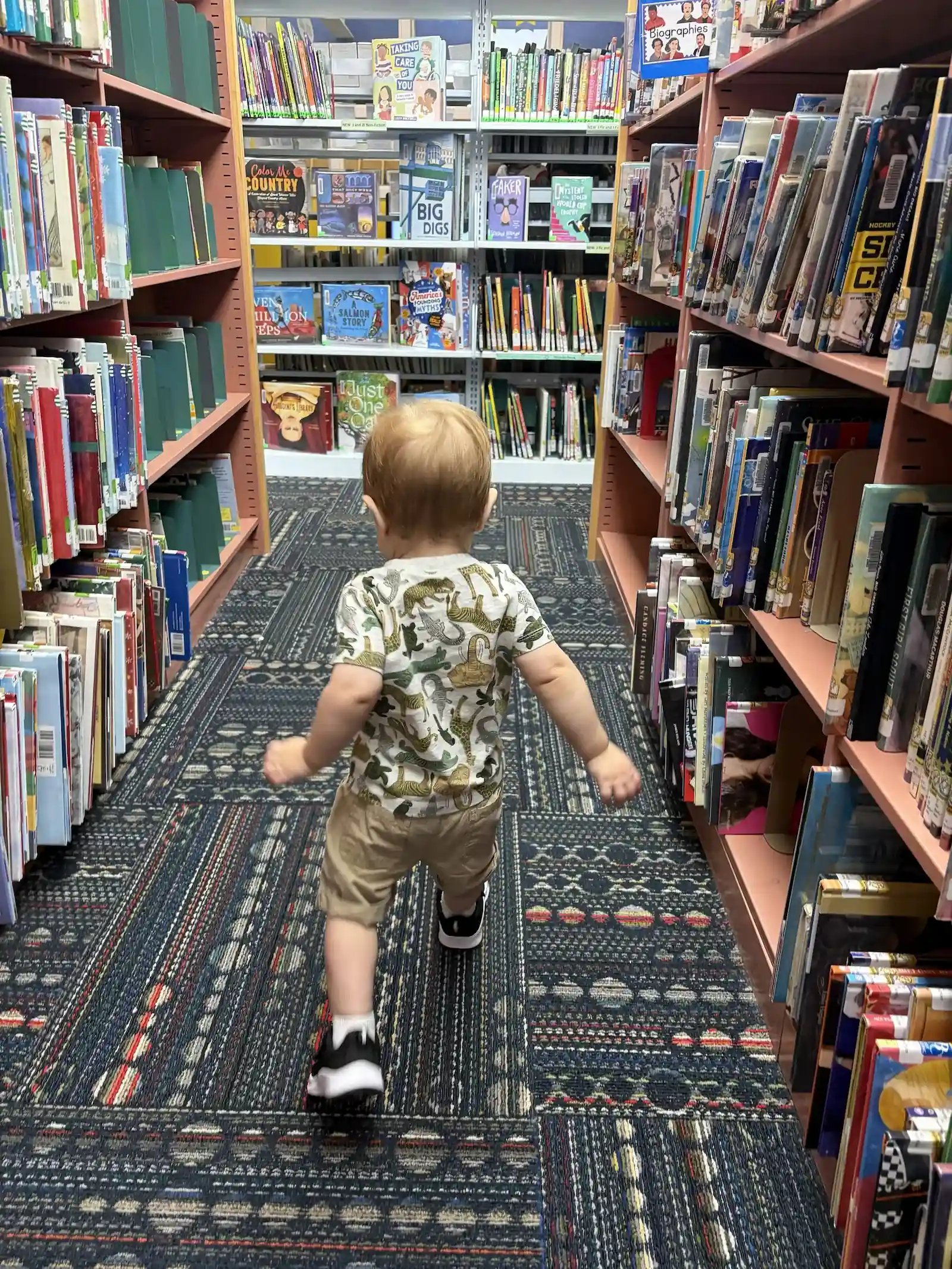 child walking through library bookshelves